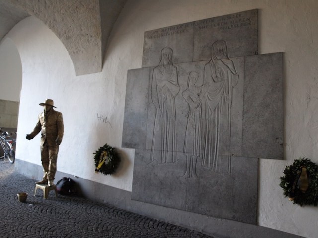 A busker, standing watch next to the ‘Night of the Broken Glass’ memorial on the side of the old city hall. 