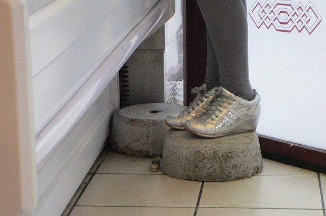 Gristmill stone step for short customers in the kebab shop. The design on the glass window is an arabesque. 