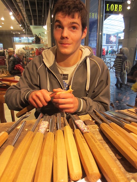 Modern day sculptor carving a donkey with his tools of trade laid out in front of him. 
