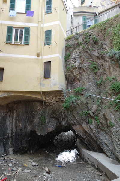 House clinging to a rockface over a creek. 