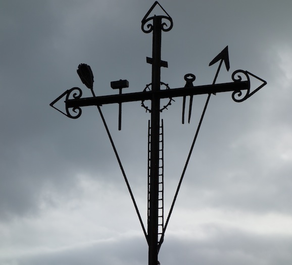 Steel cross with personal touches including, pincers, hammer and a ladder.