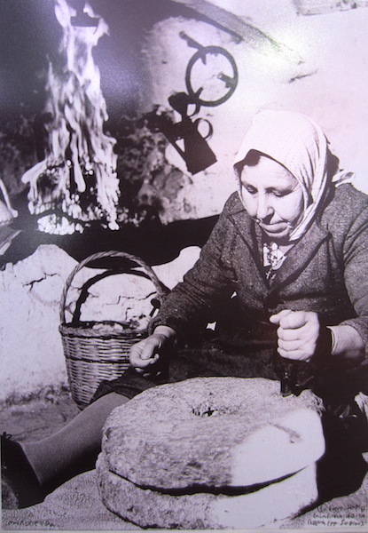 Small scale grain grinding. The grain is hand fed into the hole in the centre of the mill. 