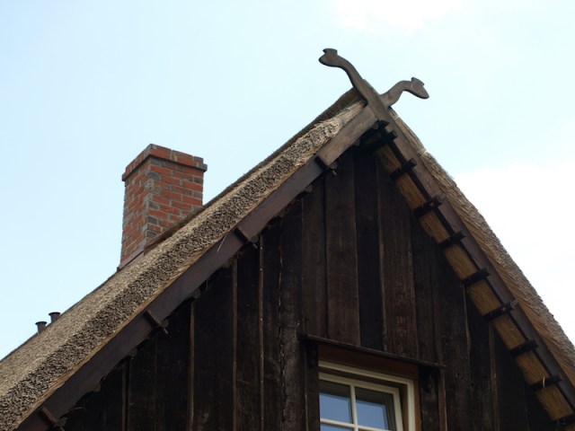 Snakehead finials on the end of a thatched roof house. 