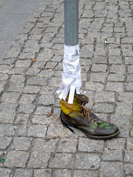 An alternative way of thinking, an eye-catching advertisement on a signpost. The side of the boot had been cut and the boot wrapped around the pole. 