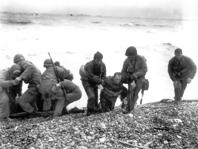 Members of an American landing unit help exhausted comrades ashore. Photo AP via via http://vcepinc.org web page