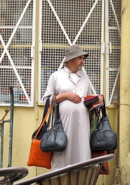 A tout with handbags and purses to sell waiting to pounce. 